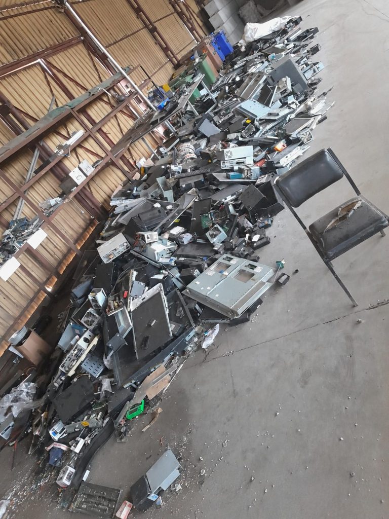 Zużyty sprzęt elektroniczny, obudowy komputerowe i podzespoły zgromadzone w hali magazynowej